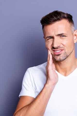 a man holding his cheek due to tooth pain