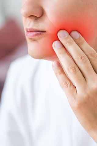 a person touching their jaw due to tooth pain